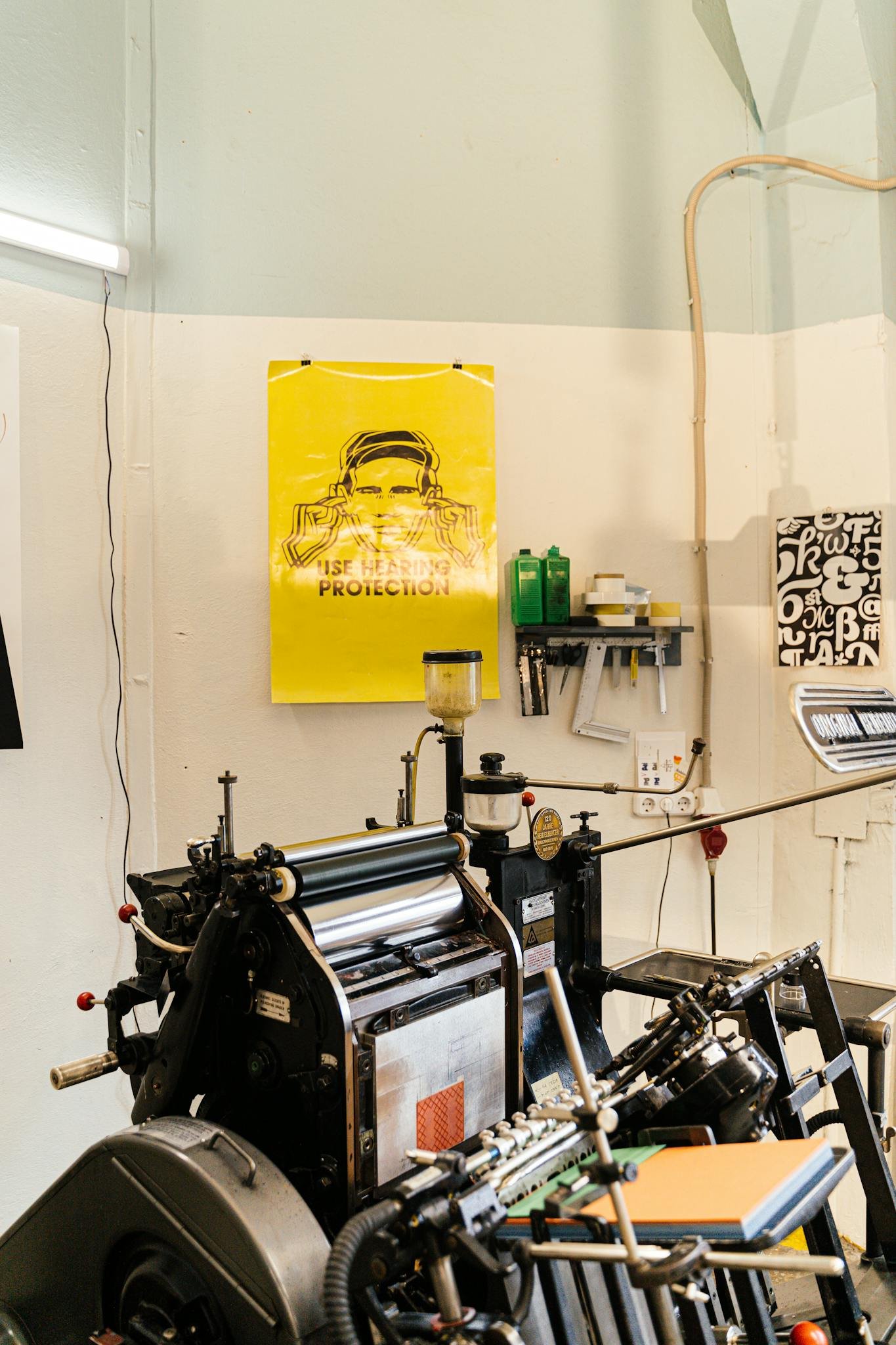 A detailed view of a professional printing press setup in a studio, highlighting equipment and posters.
